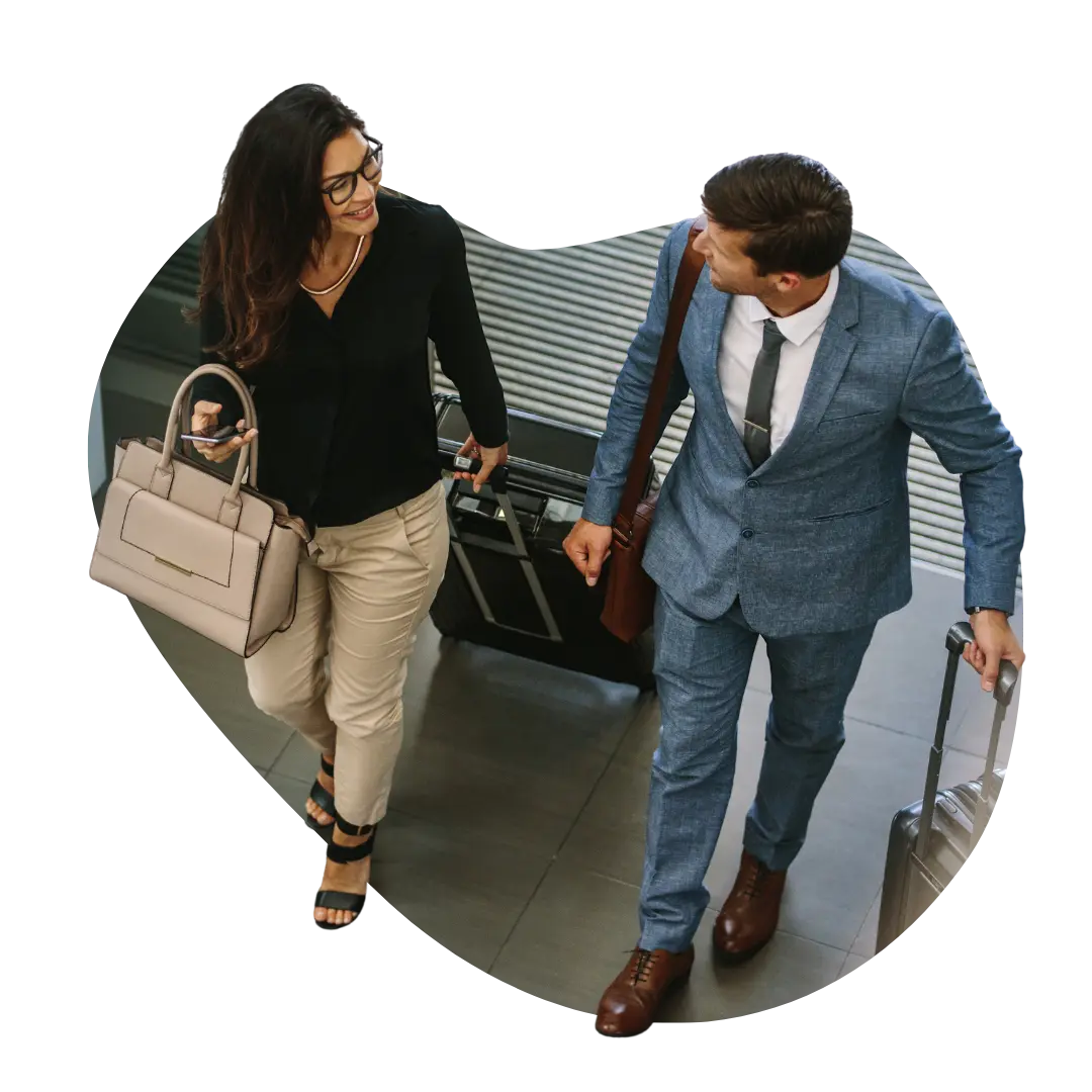 Business couple walking confidently through a hotel lobby with luggage, representing guests who feel valued through timely personalised communications